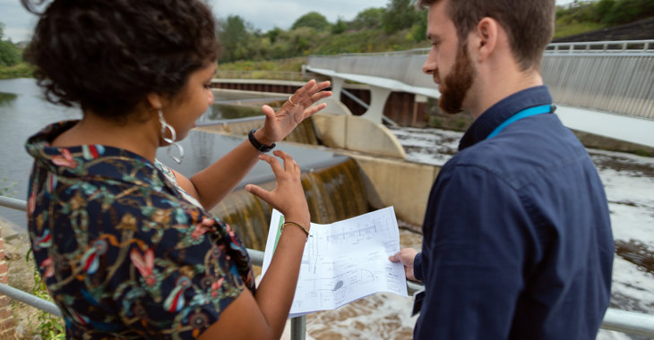 two people talking with plan at damn water - milly