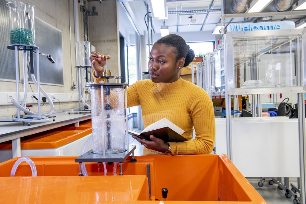 Black woman working in a lab wearing an orange jumper