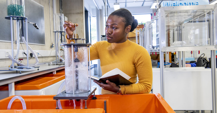 Black woman working in a lab wearing an orange jumper